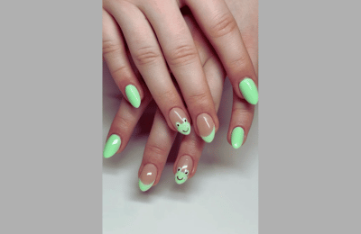 Green French tips adorned with smiley and frog designs.