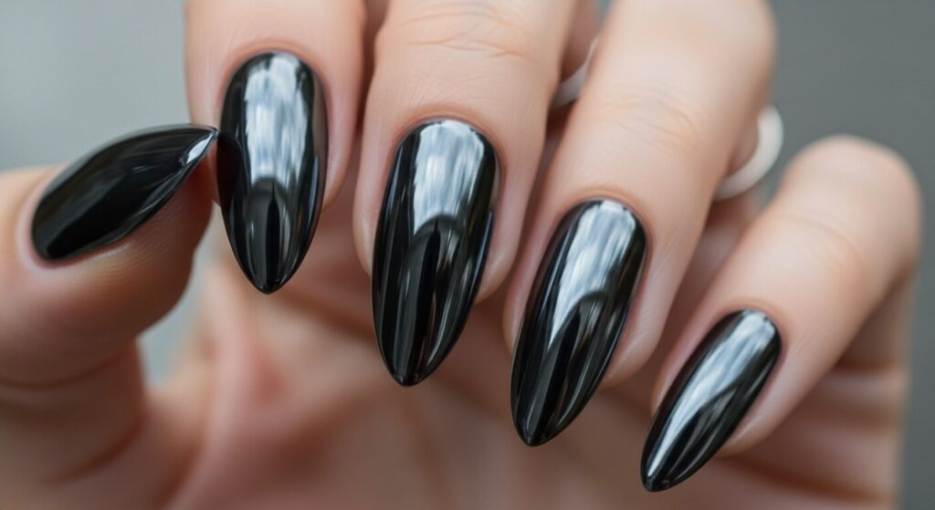 Close-up of nails featuring a black chrome nail design with a glossy, reflective metallic finish.