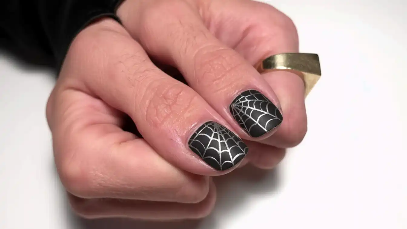 Matte black with glossy spider webs - modern Halloween spider nail designs.